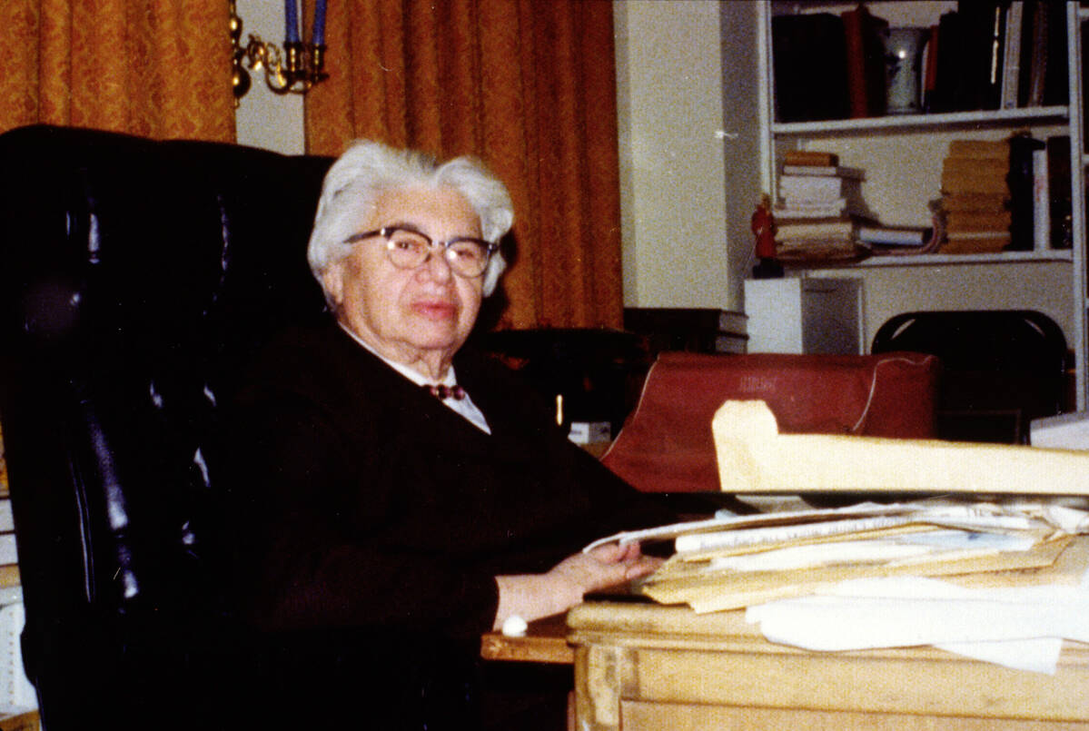 Pearl M. Hart seated at a desk stacked with papers